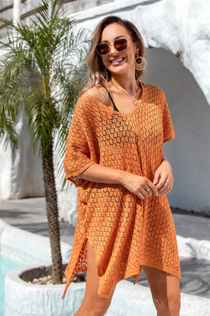 Open-knit orange beach poncho with V-neck and side slits, styled casually.