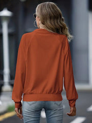 Textured ribbed raglan zip-up jacket in terracotta, with a mock neck and elastic cuffs.