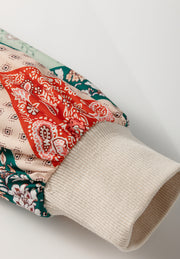 Patchwork paisley peplum knit top in beige with a ribbed cuff and gathered sleeve detail.
