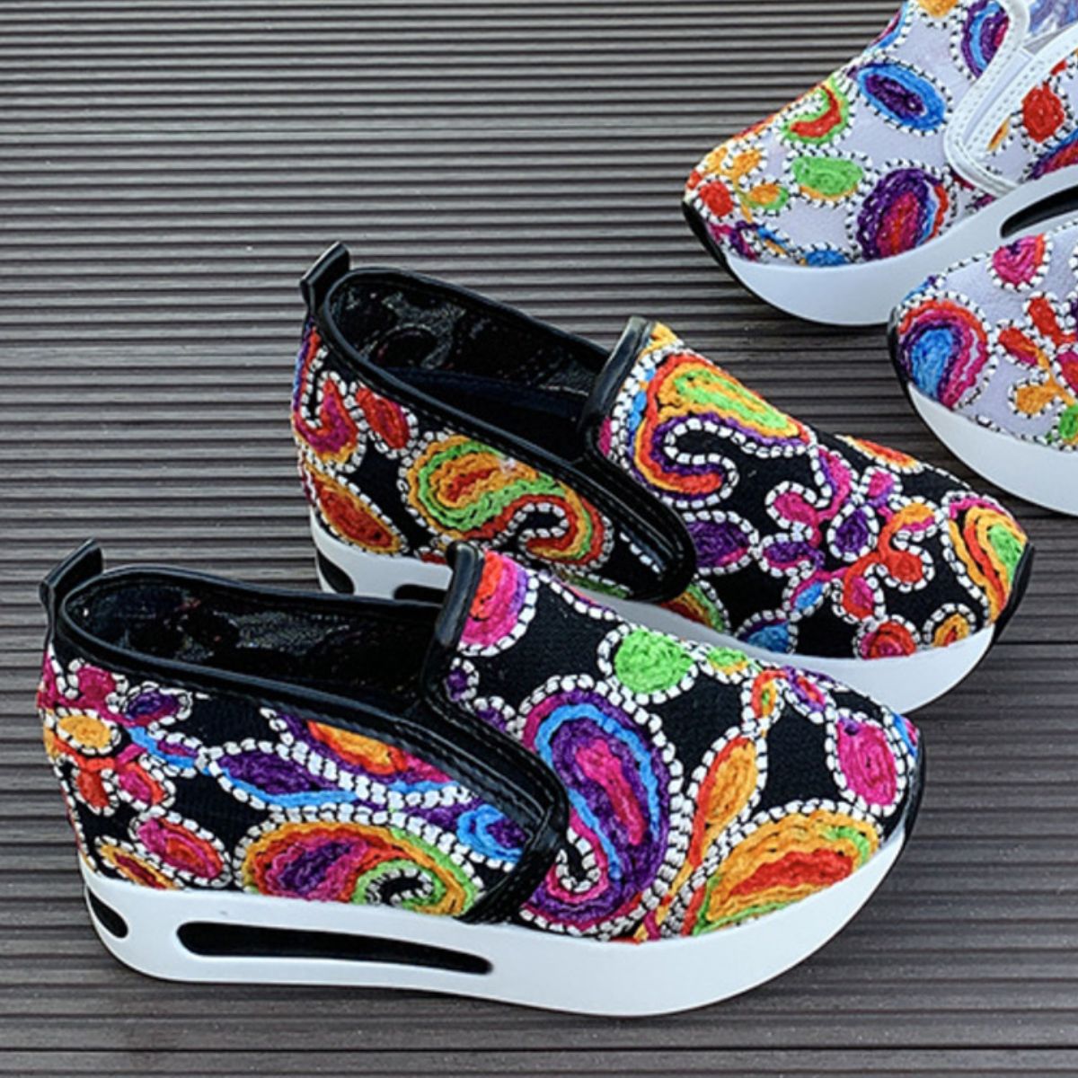 Vibrant slip-on platform sneakers with colorful paisley embroidery and white soles.