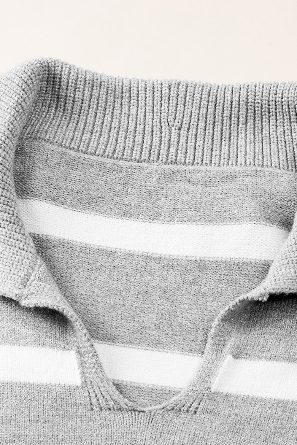 Light gray and white striped knit pullover sweater with a wide collar and V-neck detail.