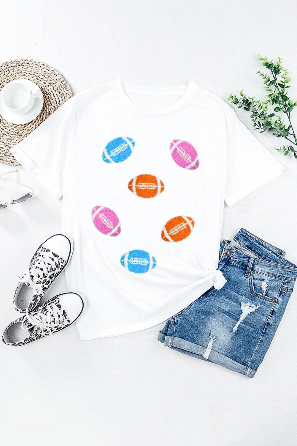 White t-shirt with rolled sleeves and scattered colorful football graphics.
