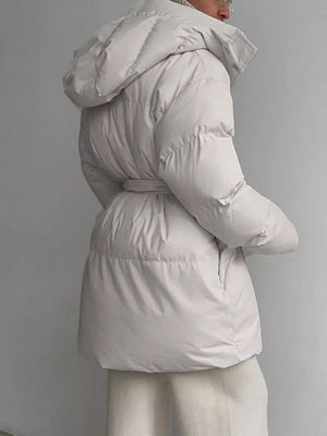 Thick puffer trench coat in ivory white with hood and belted waist.