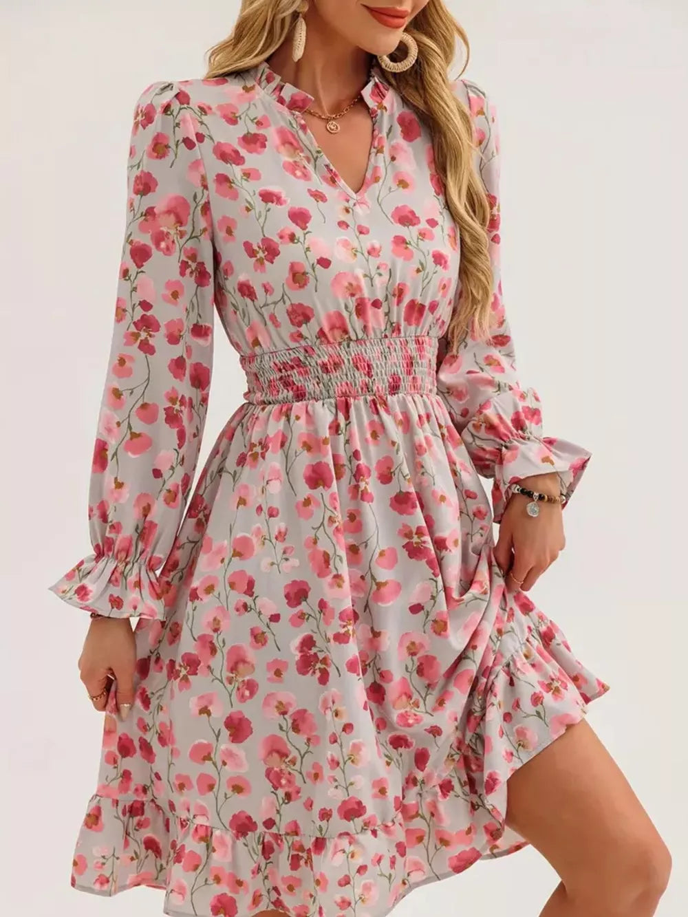 Romantic floral smocked dress in blush pink with ruffled hem and cuffs.