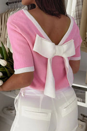 Pink knit top with white contrast trim and a large bow detail on the back.