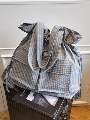 Grey plaid drawstring backpack with multiple front pockets and adjustable straps.