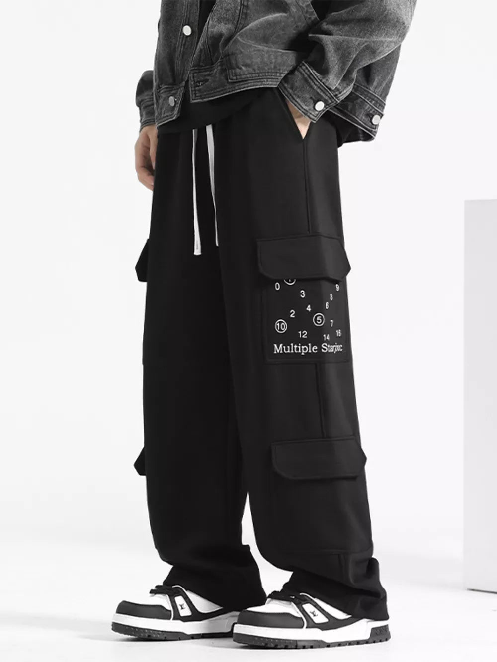 Black drawstring cargo sweatpants with multiple pockets and graphic detail.