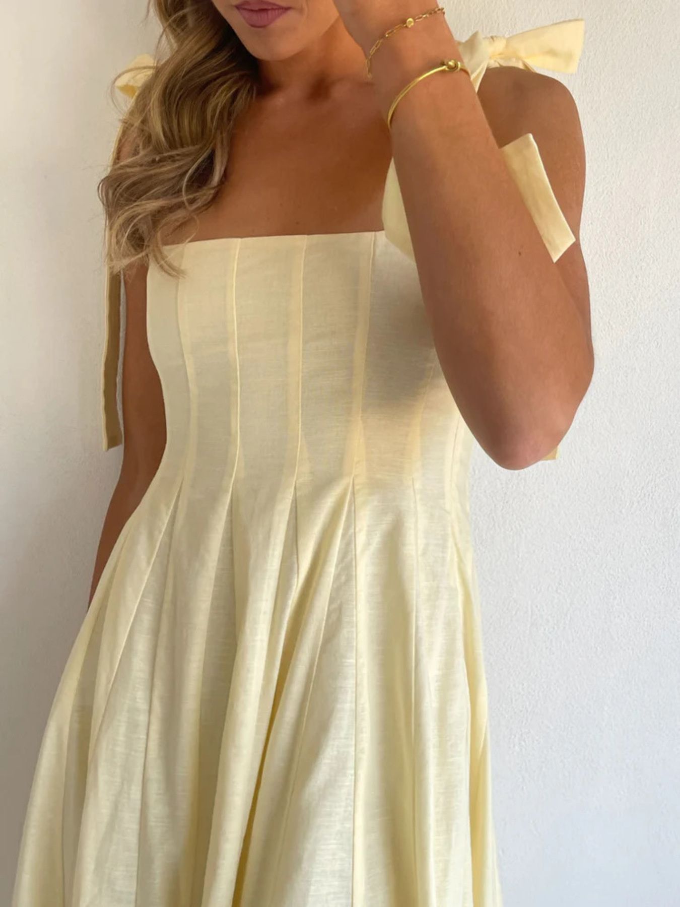 Yellow bow-tie shoulder maxi dress with a strapless bodice and pleated skirt.