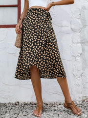 Asymmetric wrap skirt in black with abstract print, tie waist, and ruffled hem.