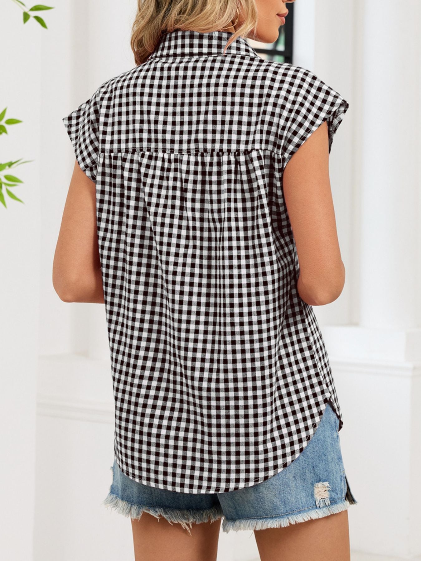 Black gingham cotton shirt with cap sleeves and button-down front, styled with denim shorts.