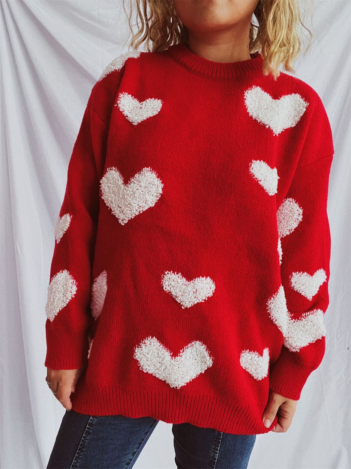 Red acrylic knit sweater with textured white heart appliqués, crew neck, long sleeves.