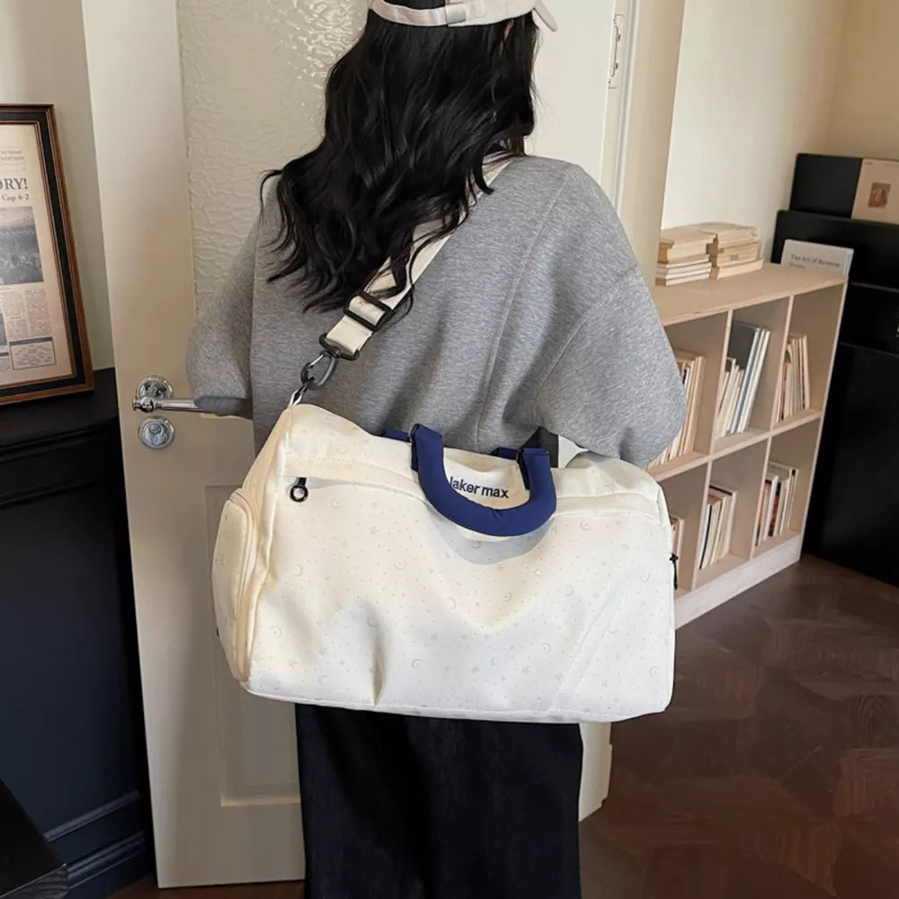 Starry Night duffel bag in cream white with crescent moon pattern and blue handles.