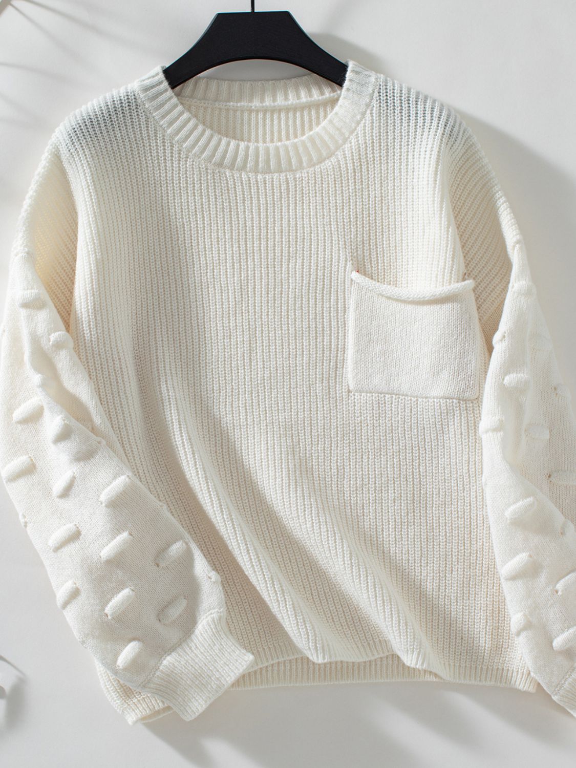 Ivory knit sweater with textured sleeve details and a chest pocket.