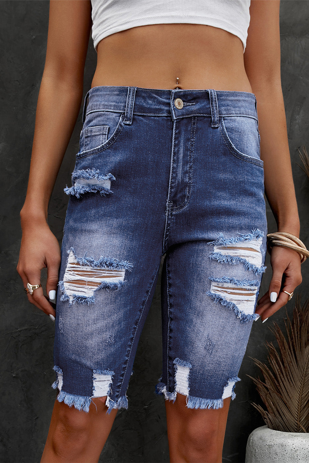 Ripped knee denim bermuda shorts in medium wash with frayed hem and distressed details.