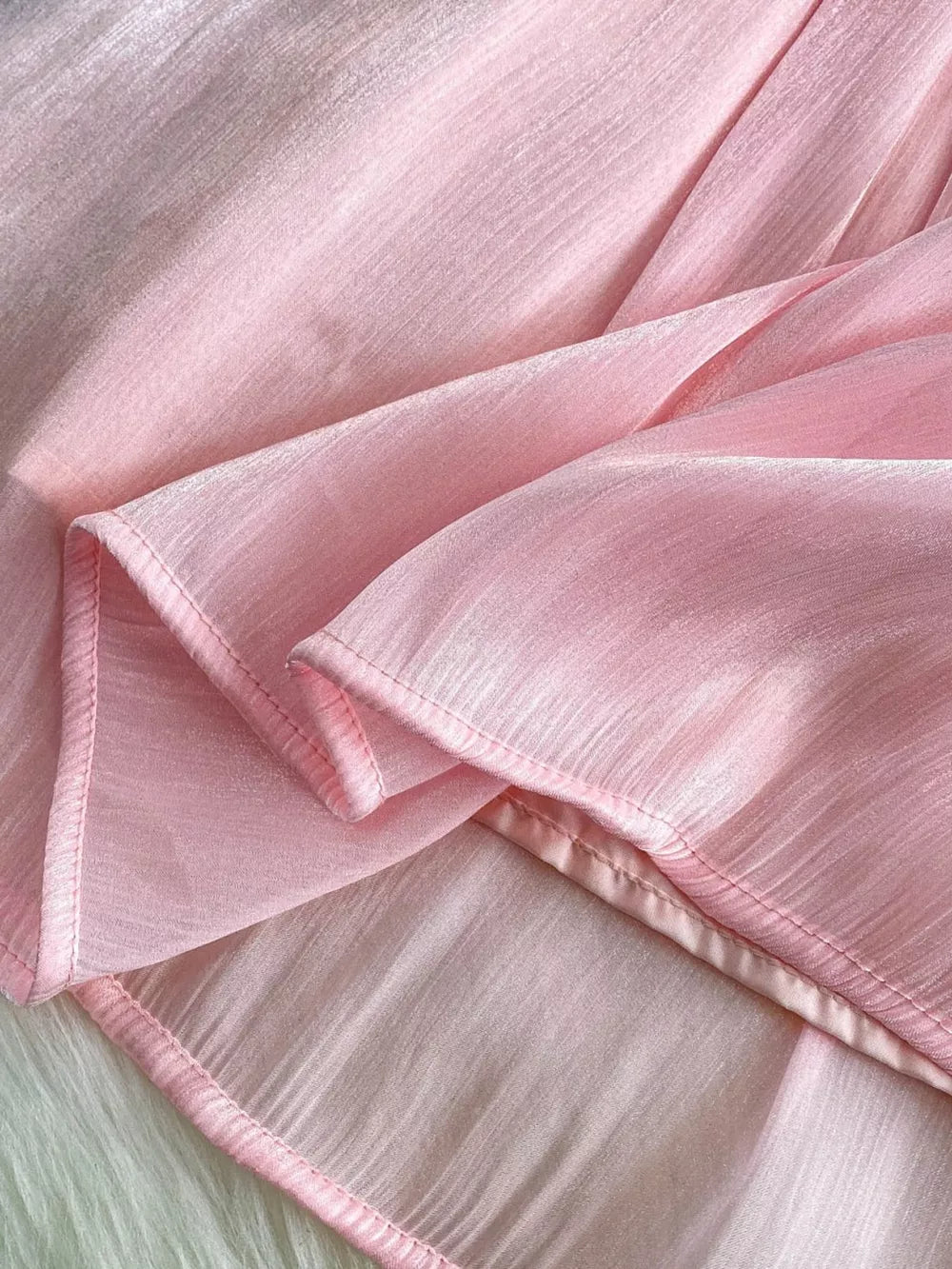 Pink sheer mesh blouse with subtle vertical texture and rhinestone embellishments.