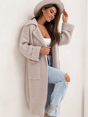 Oversized knit lapel cardigan in cream with pockets and cuffed sleeves, styled with a white top and ripped jeans.