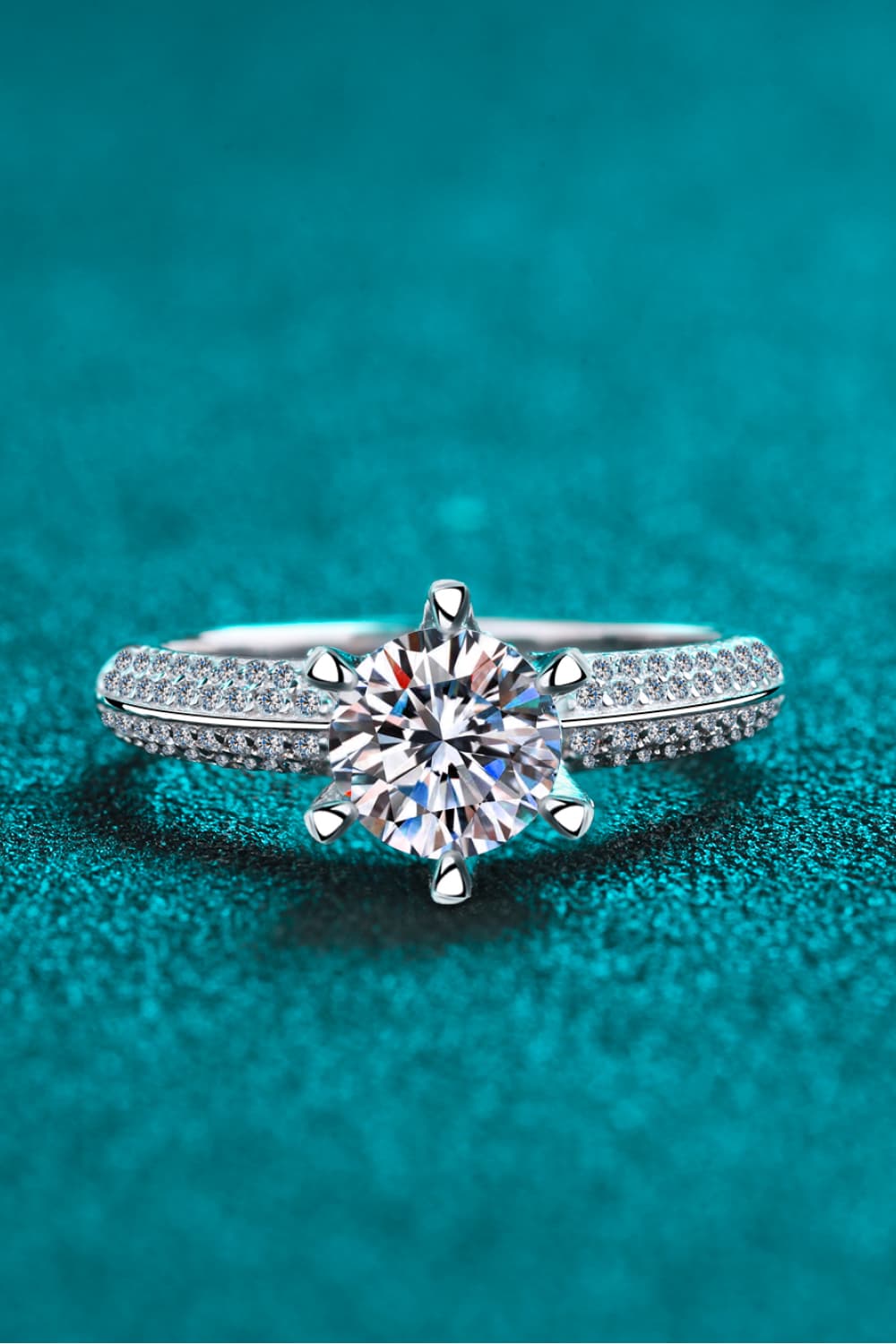 Silver pavé halo moissanite solitaire ring with six prongs.