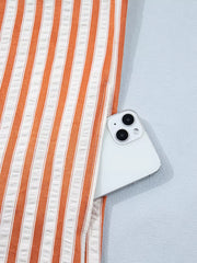 Orange and white striped shift mini dress with a pocket holding a smartphone.