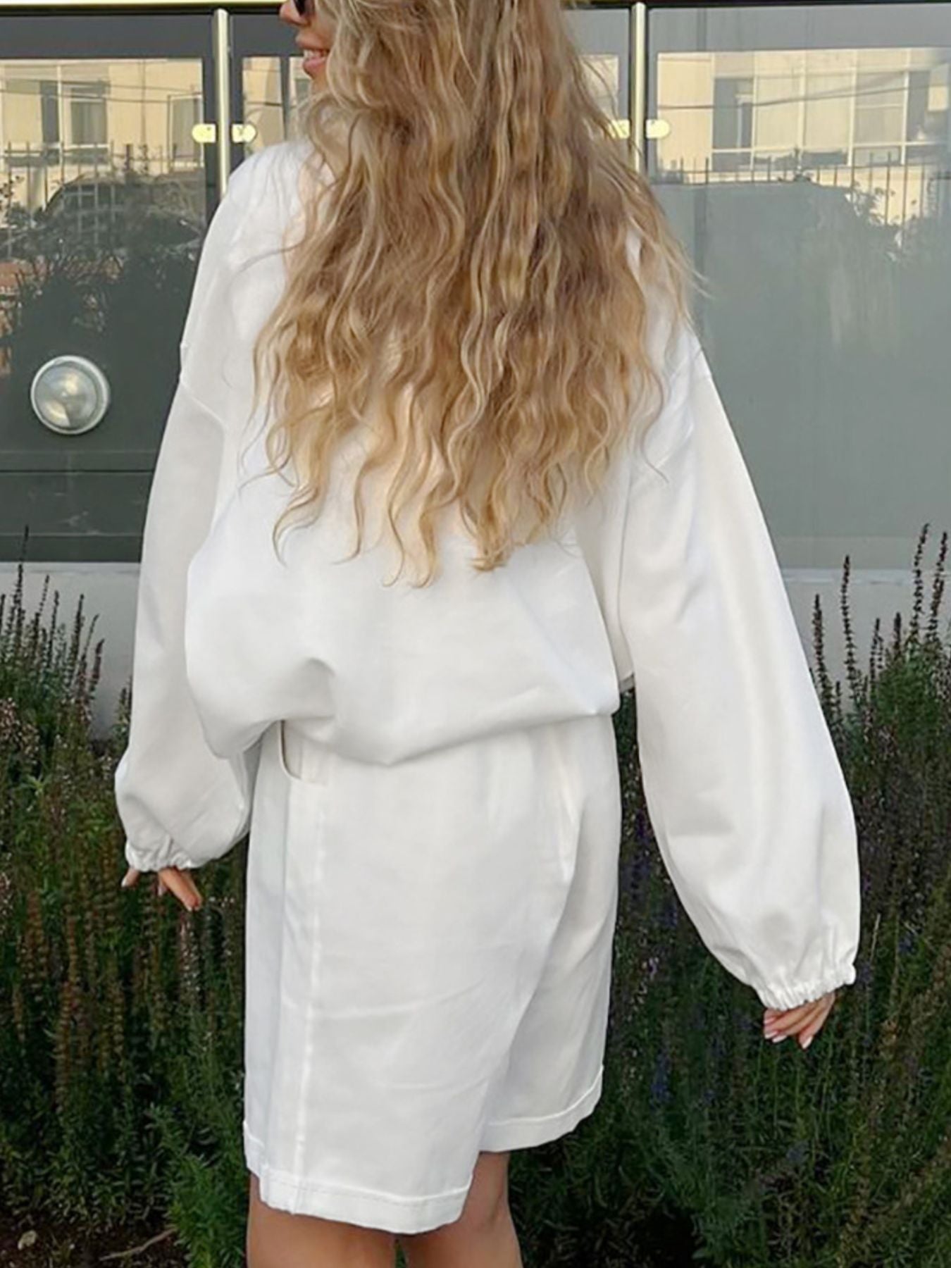 White two-piece set with snap details, featuring a loose-fit top and shorts.