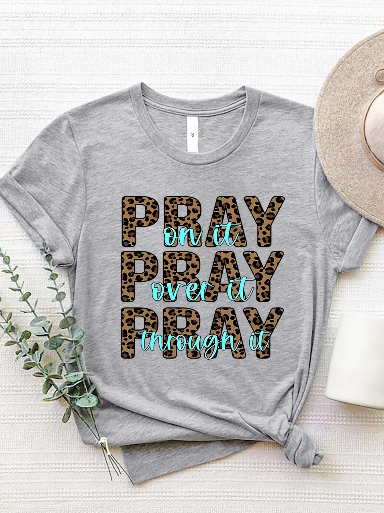 Gray graphic tee with leopard print text that reads "PRAY on it PRAY over it PRAY through it