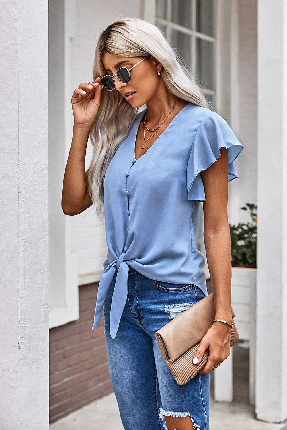 Pastel blue tie-front blouse with ruffle sleeves and button detail.