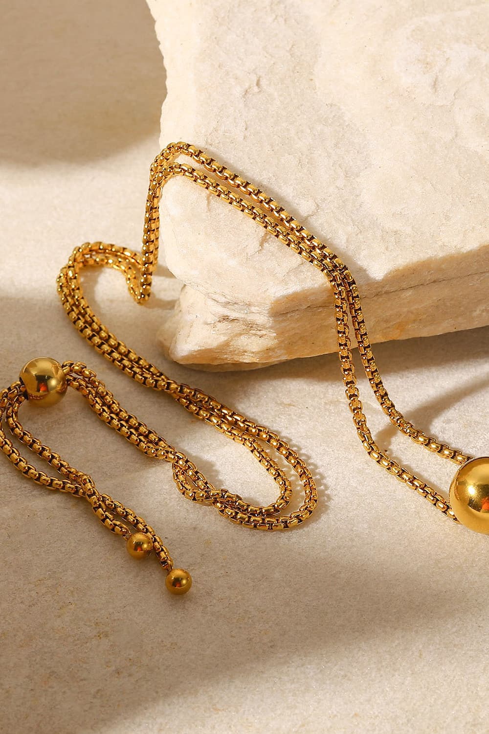 Gold orb pendant necklace with adjustable chain and bead details.