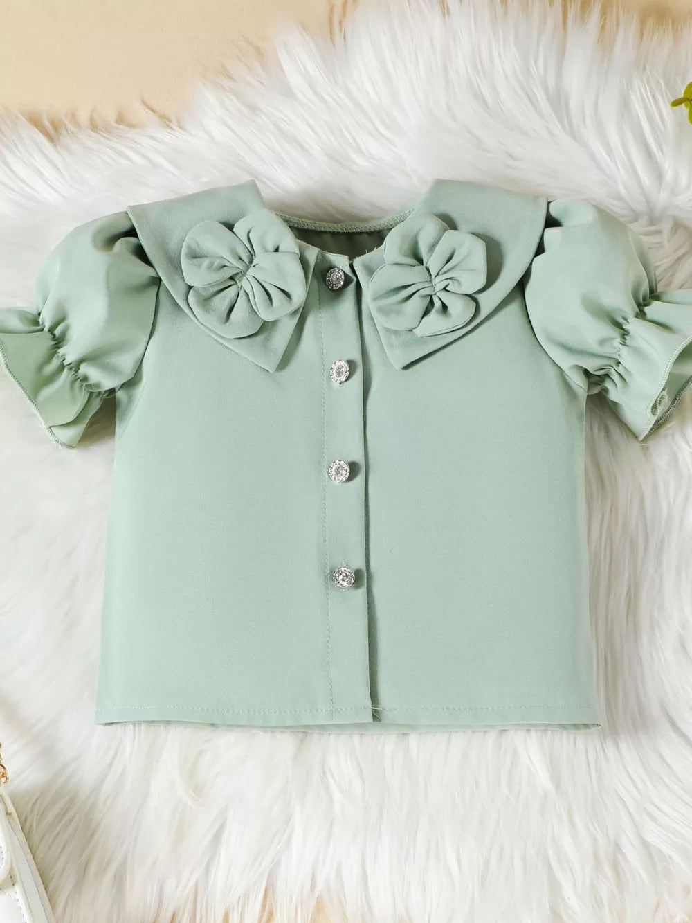 Green toddler top with ruffled sleeves, floral collar, and jeweled buttons.