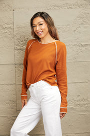 Caramel waffle knit raglan sweater with contrast stitching and ruffled cuffs.