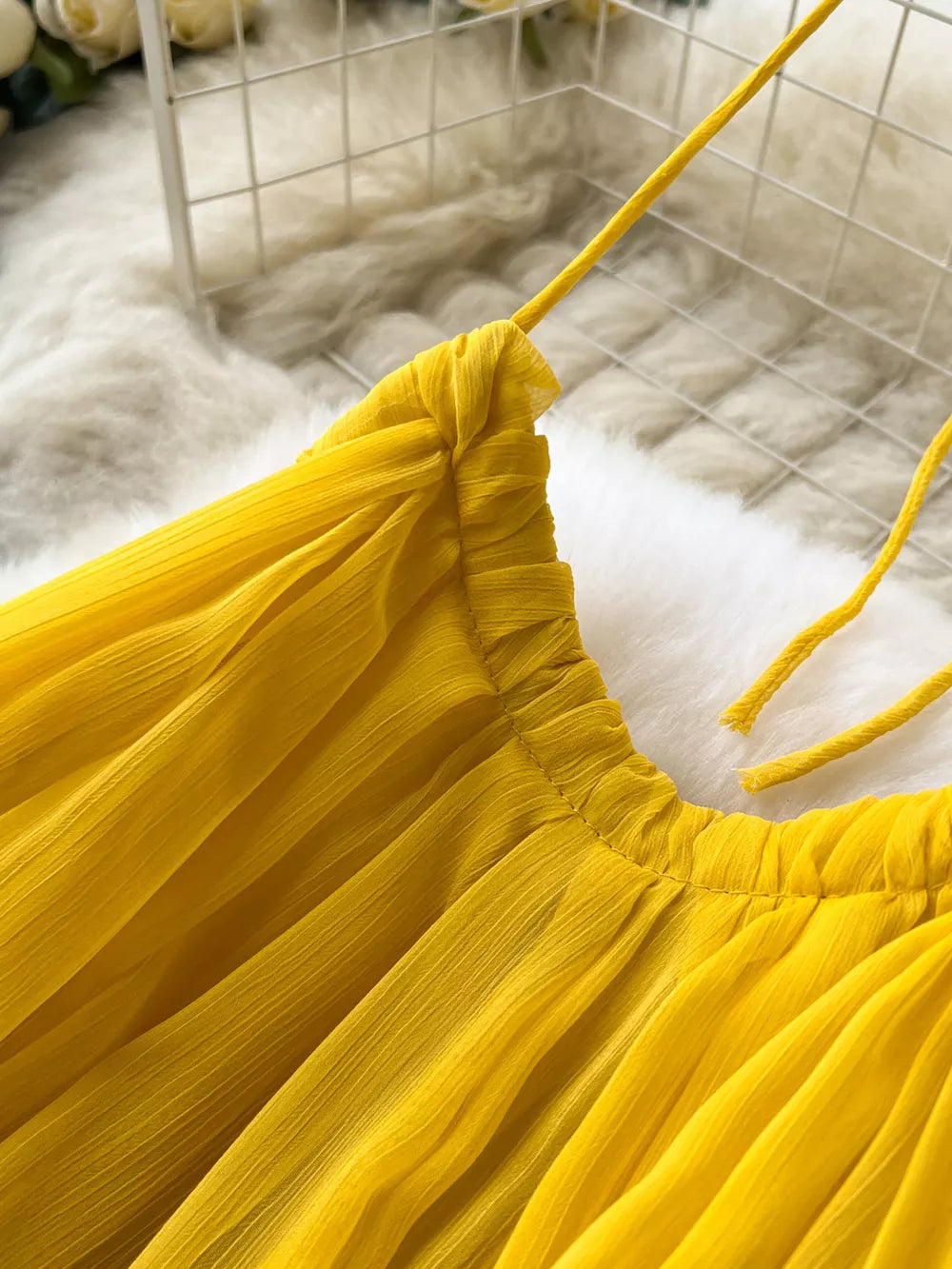Yellow chiffon halter dress with ruched neckline and tie straps.