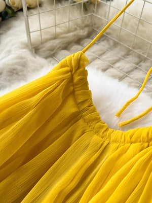 Yellow chiffon halter dress with ruched neckline and tie straps.