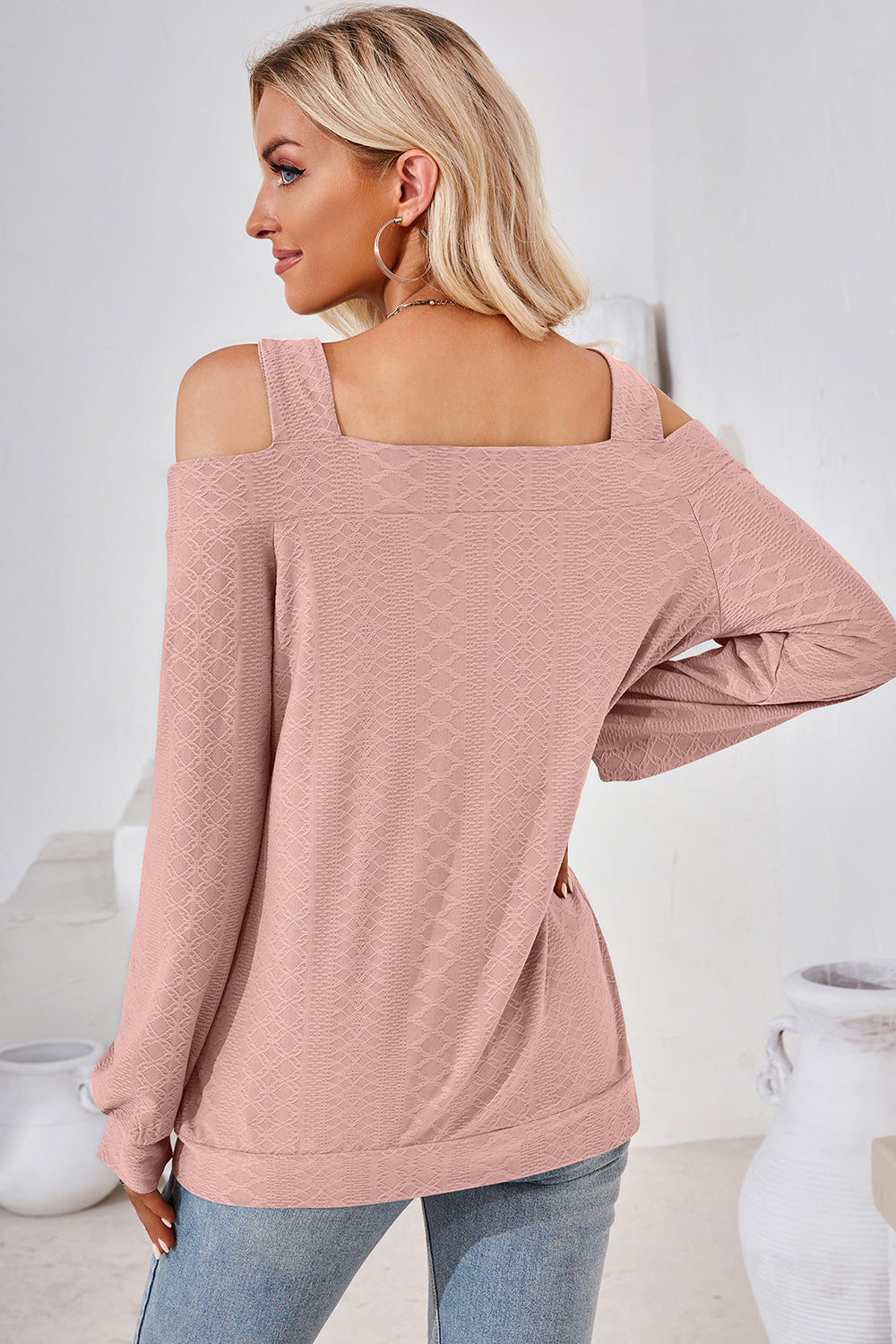 Blush pink textured blouse with cutout shoulders and square neckline.