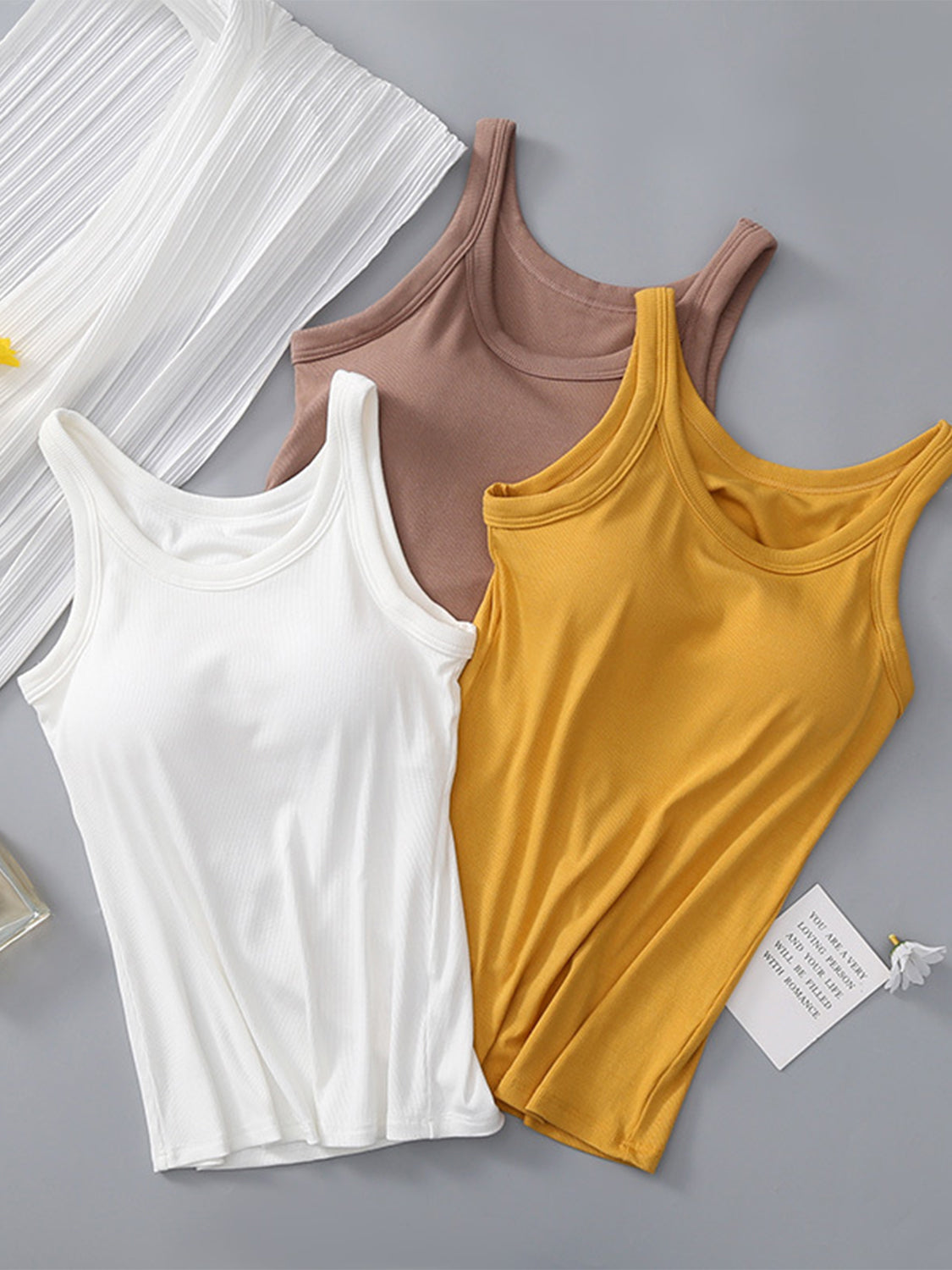 Ribbed knit tank tops in white, mustard, and brown with built-in bras.