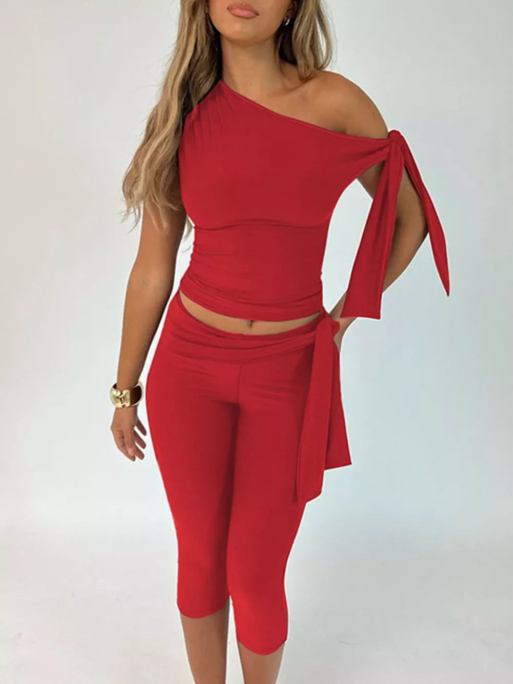 Red asymmetrical one-shoulder top with tie sleeves and matching capri pants.