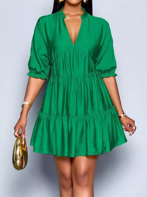 Green tiered mini dress with notched V-neck and puff sleeves.