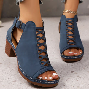Navy blue criss-cross cut-out block heel sandals with ankle strap and buckle detail.