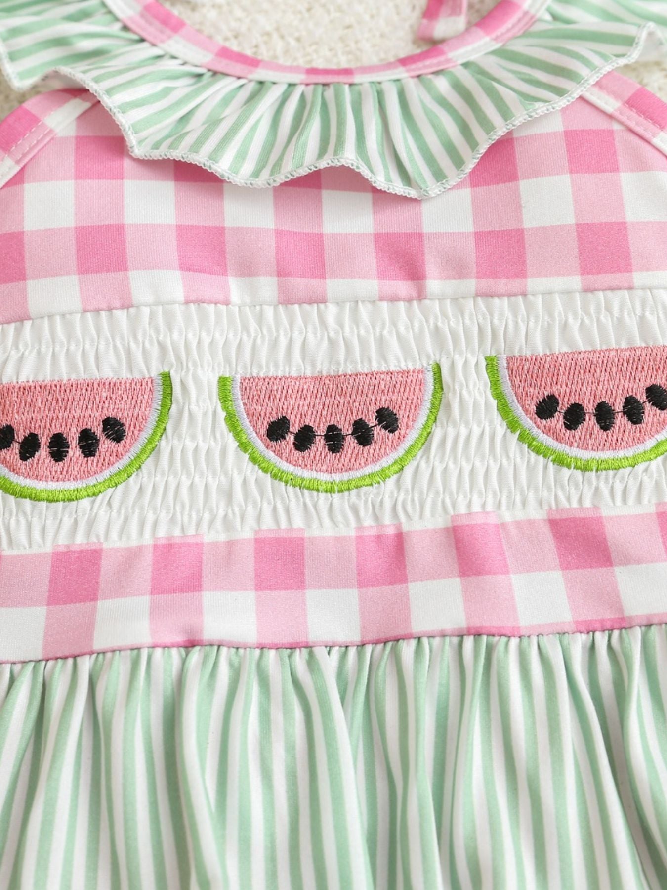 Baby one-piece swimsuit with pink gingham, smocking, and watermelon embroidery.