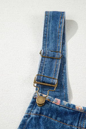 Denim overalls with floral print trim and brass hardware.