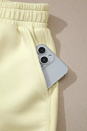 Yellow two-piece set shorts with elastic waistband and a phone in the pocket