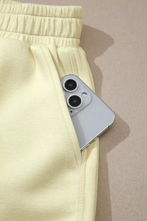 Yellow two-piece set shorts with elastic waistband and a phone in the pocket