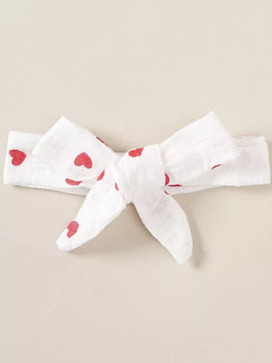White baby headband with red heart print and a knot bow detail