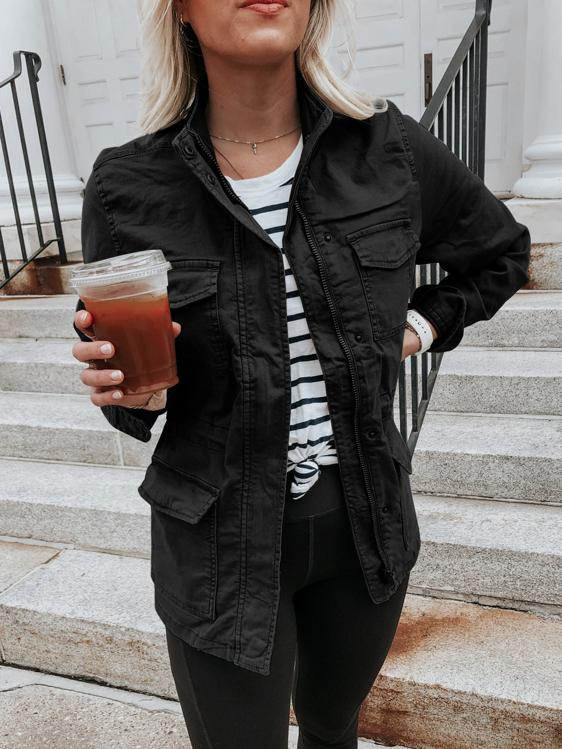 Black utility jacket with multiple pockets and a stand collar, worn over a striped tee.
