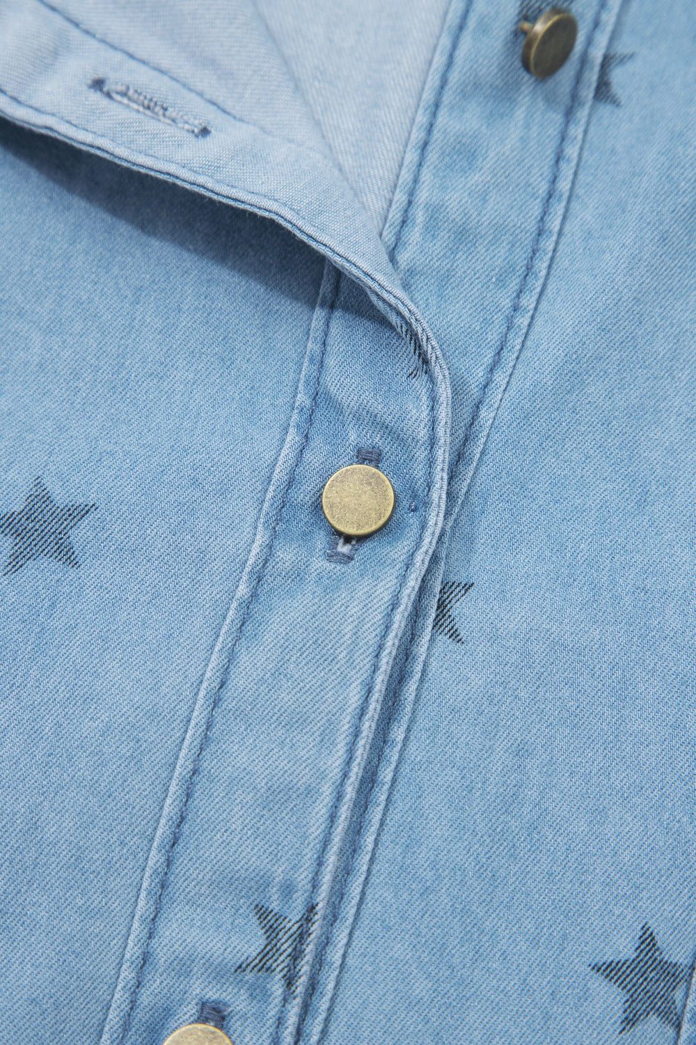 Light blue denim shirt with black star print, button front, and brass button detail.