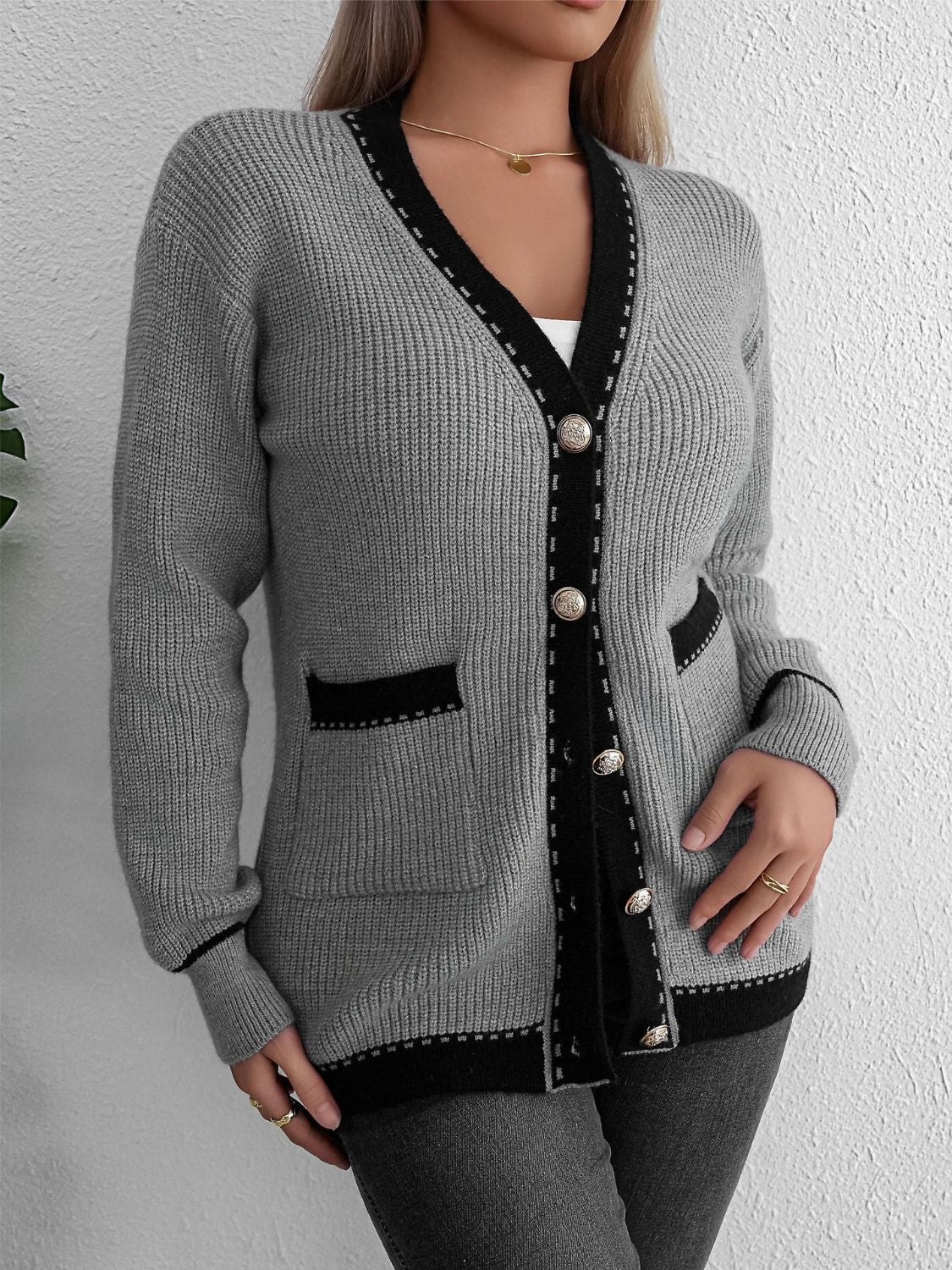 Gray knit cardigan with black contrast trim and gold buttons, featuring pockets.
