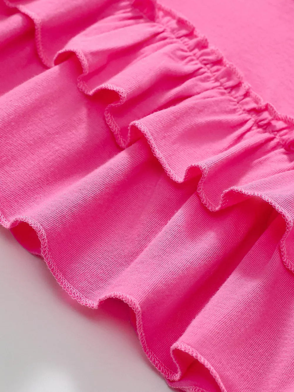 Pink toddler dress with double-layered ruffled hem detail, cotton fabric.