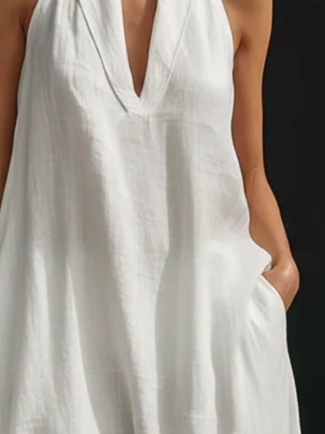 White halter neck maxi dress in cotton linen with pockets and V-neckline.