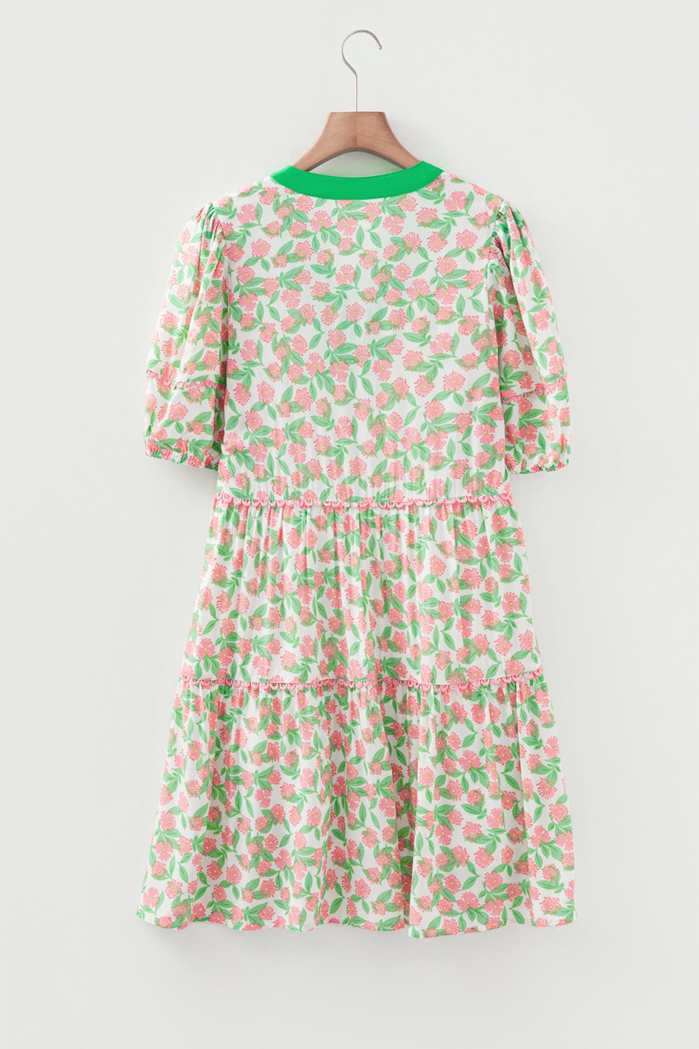 Women's tiered mini dress with puff sleeves, green neckline, and pink floral print.