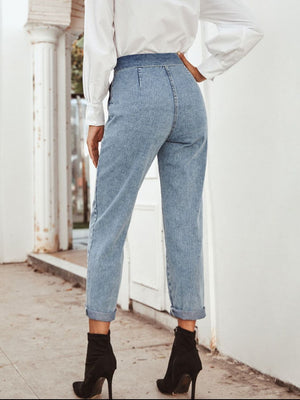 Light wash denim paperbag waist tapered trousers with cuffed hems.