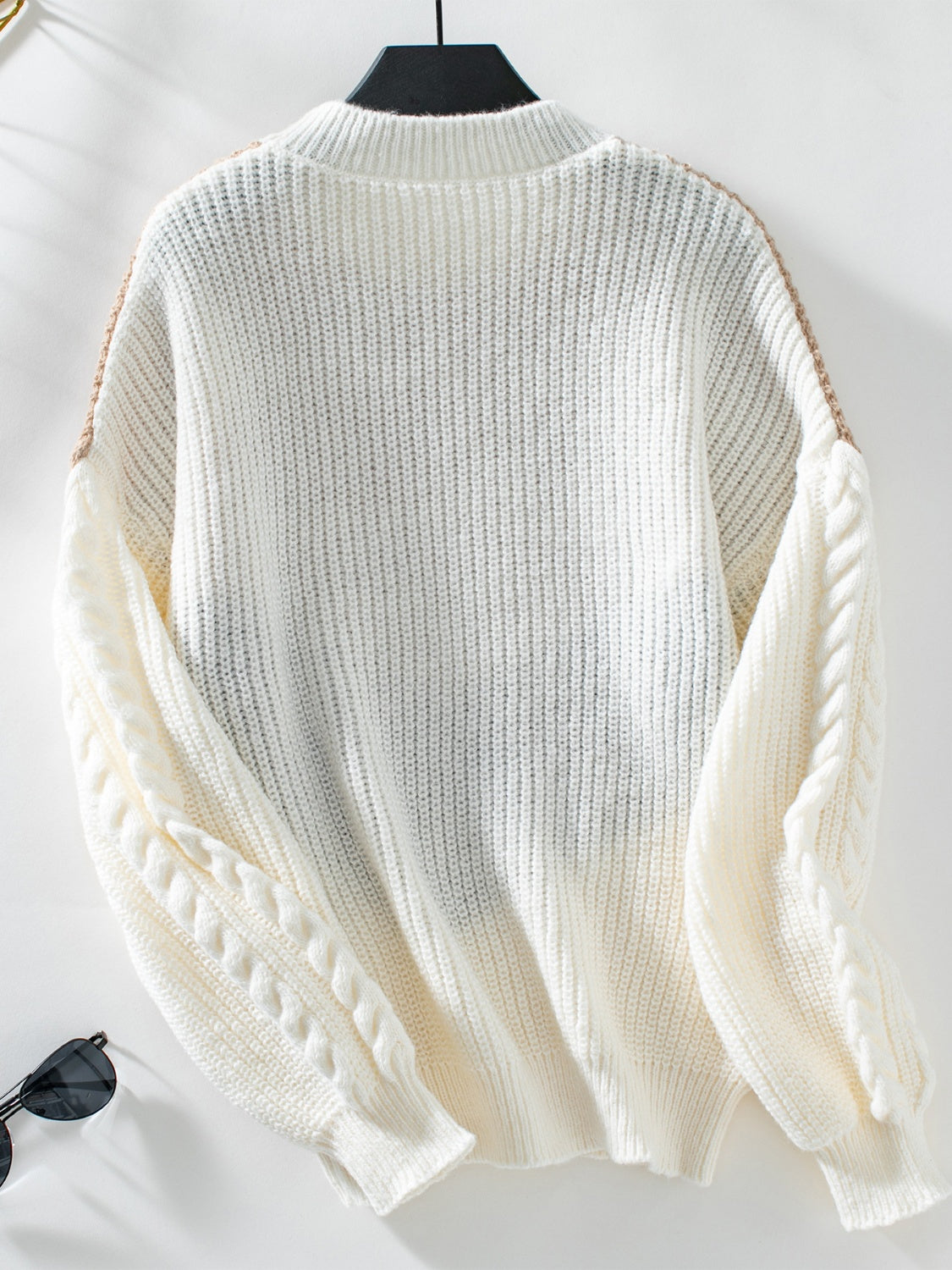 White cable knit sweater with tan accents on shoulders and sleeves.