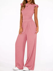 Pink maternity two-piece ensemble with ruffled cap sleeves, ruched waist, and wide-leg pants.
