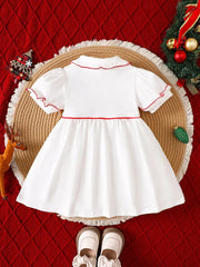 White baby dress with red trim, puff sleeves, and ruffled collar.
